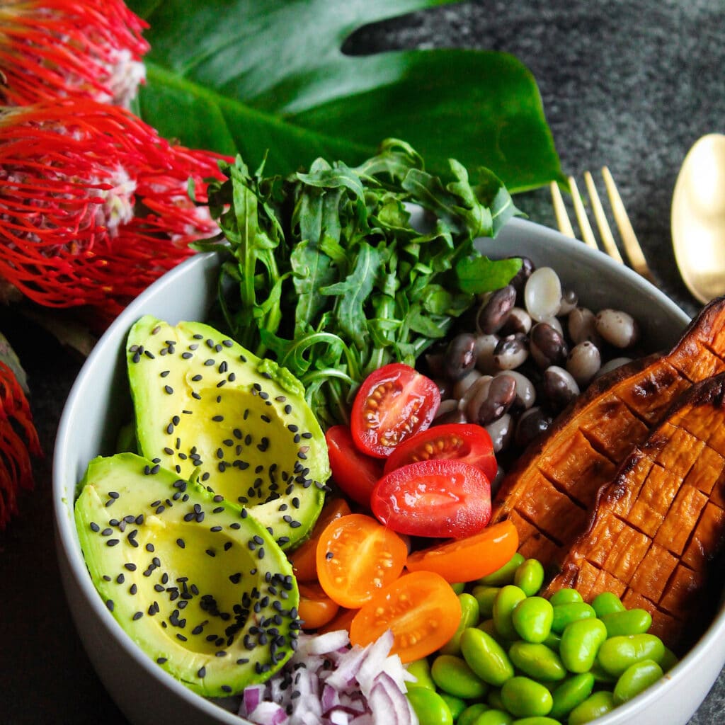 Buddha bowl med avocado, rødløg, edamame bønner, sød kartoffel, tomat og rucola