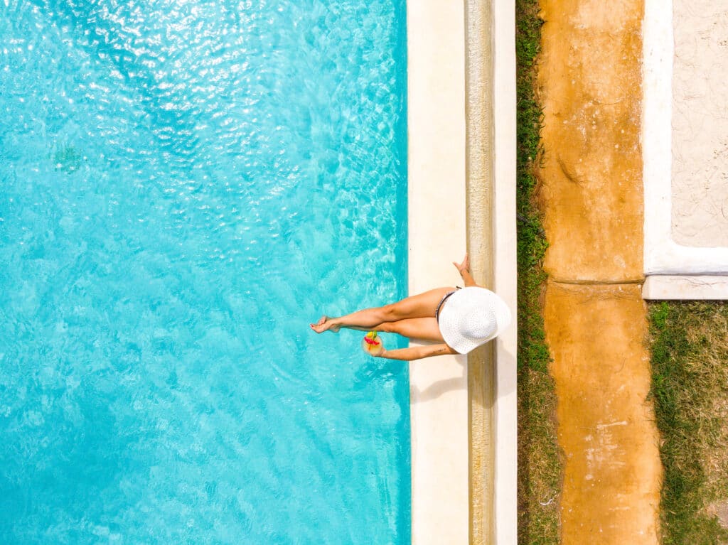 kvinde med hat og drink ved poolen på yogarejse til Zanzibar