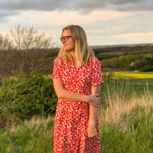 Mindful Cathrine i blomstret kjole i aftenlys med marker i baggrunden