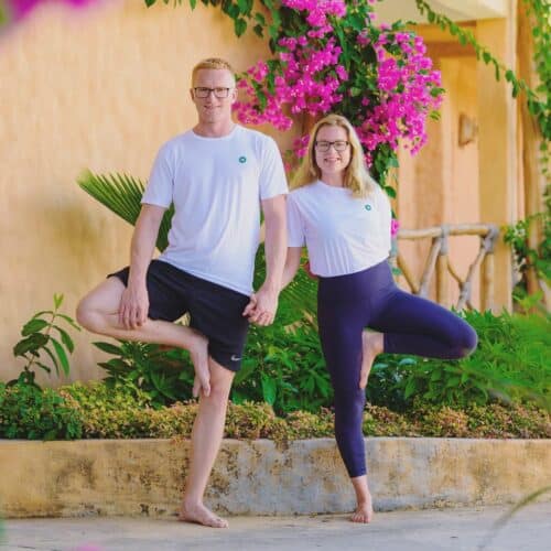 Tommy og Cathrine står i træets stilling og hodler i hånden i haven på yogarejse til Zanzibar