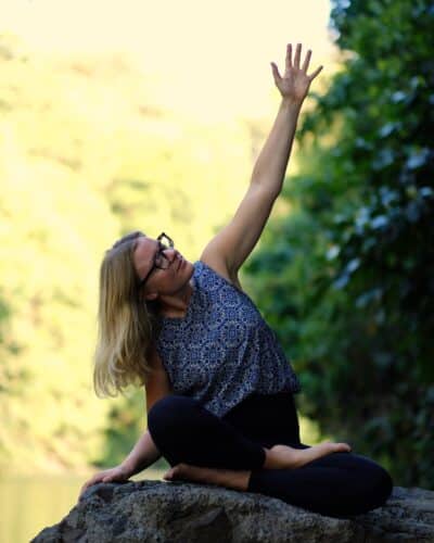 Cathrine laver organ yoga på en sten ved en flod på Bali