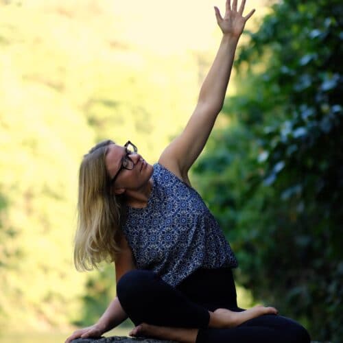 Cathrine laver organ yoga på en sten ved en flod på Bali