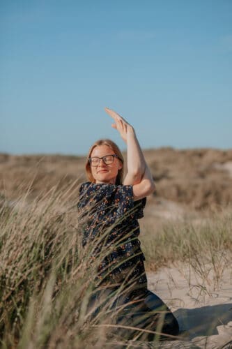 Cathrine laver yogaøvelsen komulearme i klitterne i Vestjylland