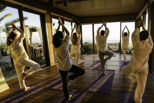 Yogaelever i hvidt tøj laver træets stilling på Yoga Retreat i Marokko