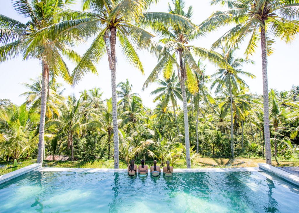 yogaelever i infinity pool med udsigt til palmer og rismarker på yogauddannelse på Bali