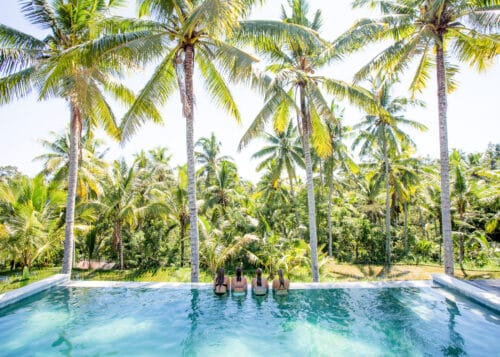yogaelever i infinity pool med udsigt til palmer og rismarker på yogauddannelse på Bali
