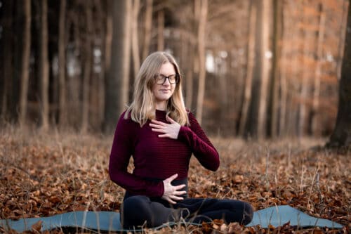 Cathrine laver åndedrætsbevidsthed i en skov om efteråret
