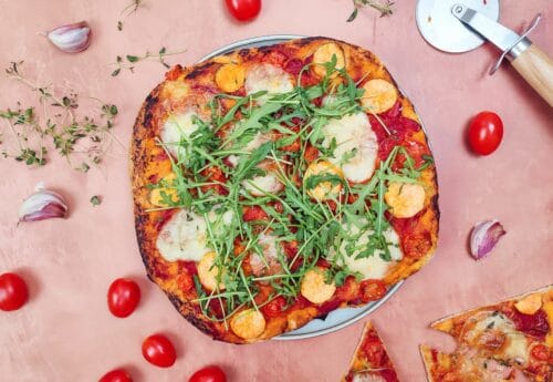 Sprød og sund vegetar pizza med søde kartofler, tomat, rødløg, hvidløg, timian og rucola