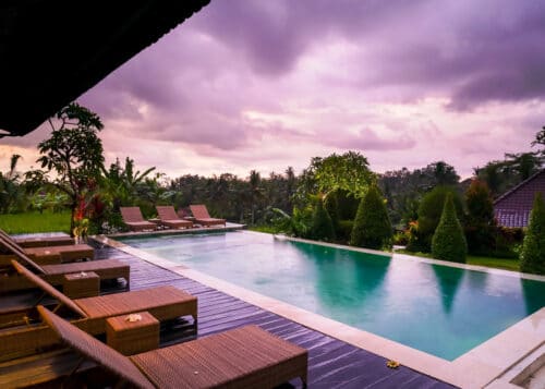 Pool, palmer og rismarker i solnedgang på yogauddannelse på Bali