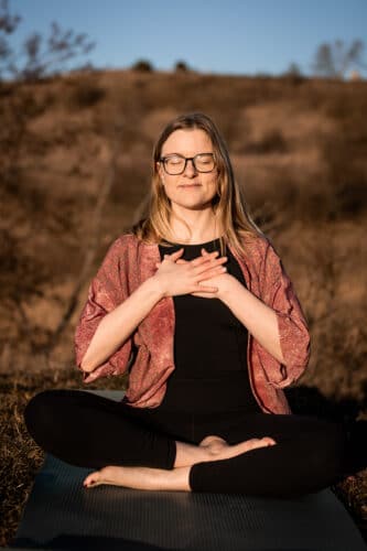 Cathrine sidder udenfor og er taknemmelig for at få energi med yoga og meditationer til de syv chakraer